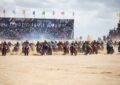 Départ massif de l’Enduro del Verano 2026 à Villa Gesell en Argentine, des centaines de pilotes motos s’élancent sur la plage dans un nuage de sable.